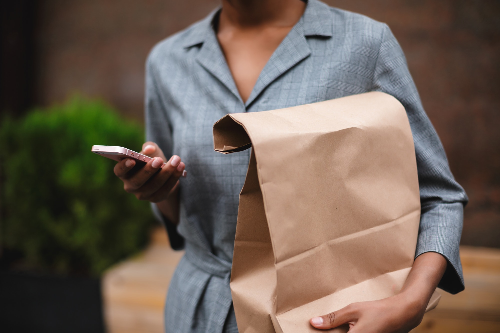 Close up photo of woman body in gray dress standing and holding paper bag