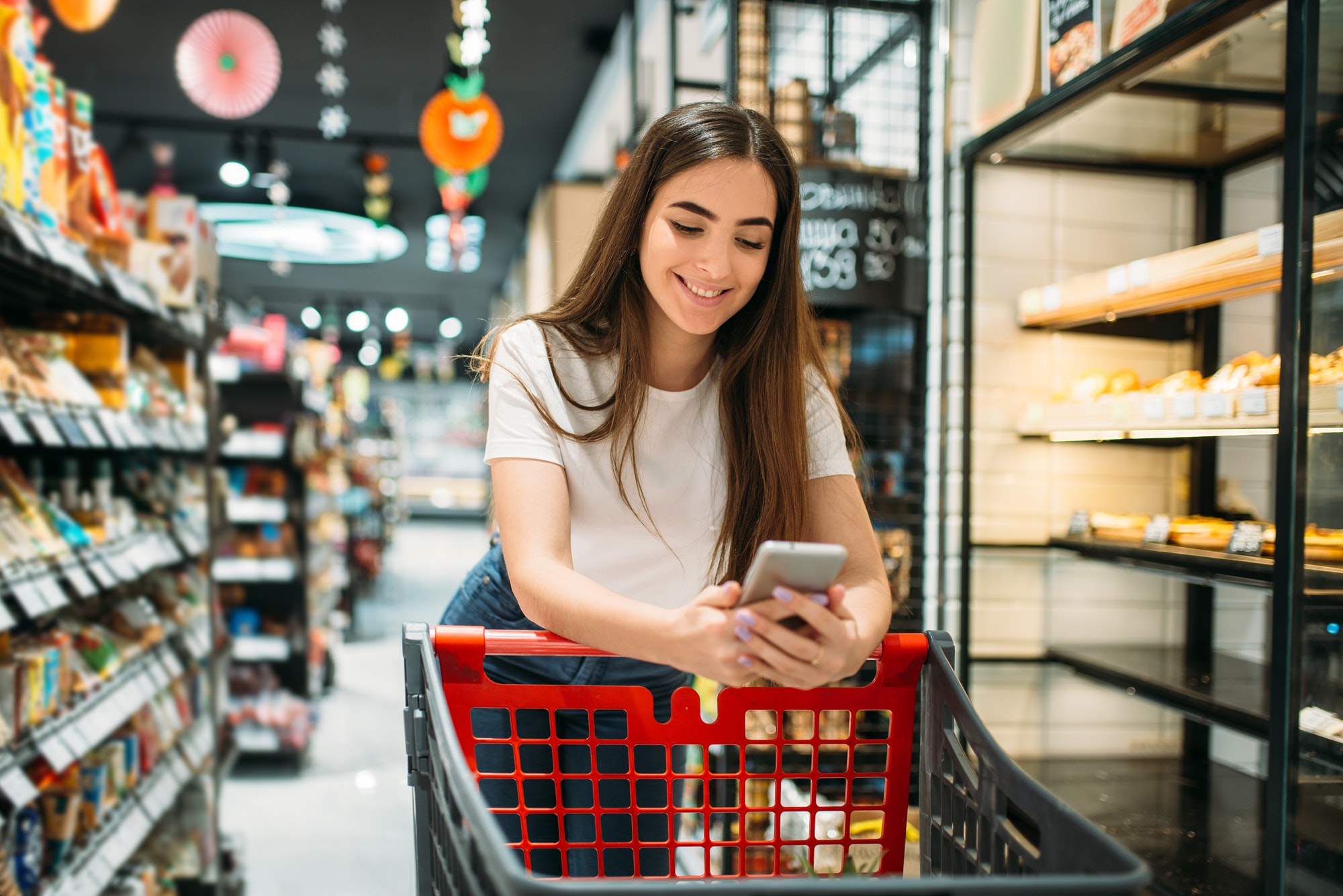 Female customer uses mobile phone in supermarket